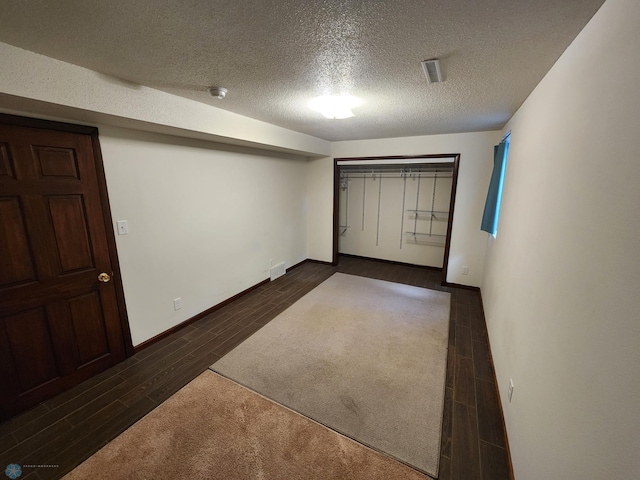 interior space with a textured ceiling and dark hardwood / wood-style flooring