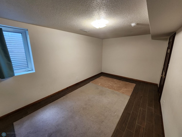 unfurnished room with a textured ceiling and dark hardwood / wood-style flooring