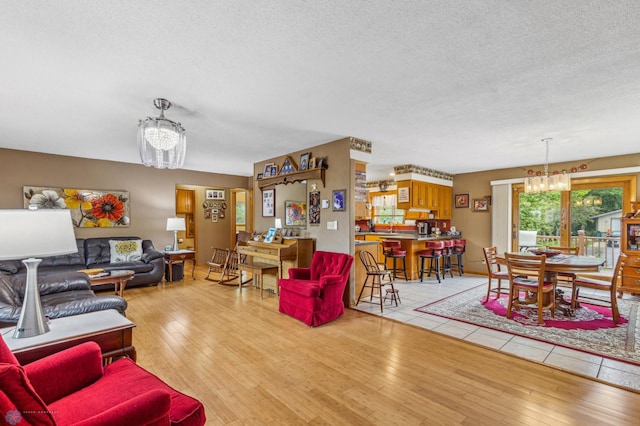 living room featuring light hardwood / wood-style floors, a textured ceiling, and a chandelier