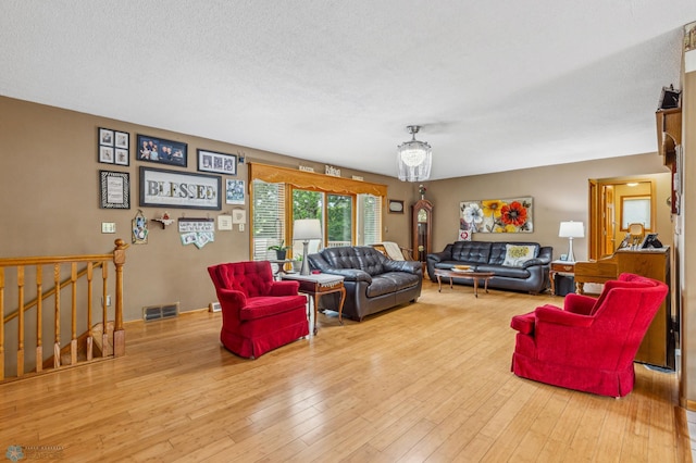 living room featuring hardwood / wood-style flooring, a chandelier, and a textured ceiling