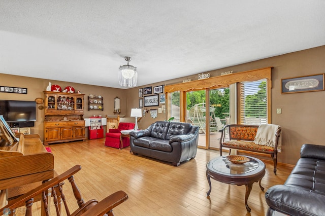 living room with light hardwood / wood-style floors, a notable chandelier, and a textured ceiling