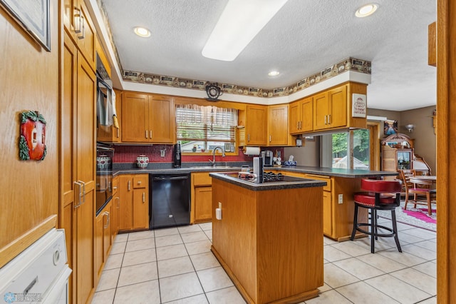 kitchen with light tile patterned floors, a kitchen island, a textured ceiling, a kitchen breakfast bar, and dishwasher