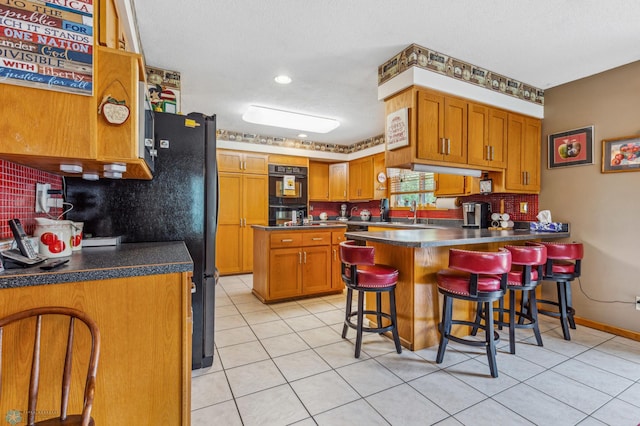 kitchen with a breakfast bar, light tile patterned flooring, decorative backsplash, and kitchen peninsula