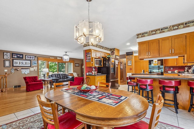 dining area with light tile patterned flooring and an inviting chandelier