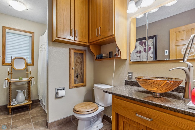 bathroom featuring vanity, a textured ceiling, tile patterned flooring, and toilet