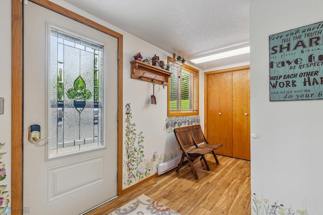 entryway with plenty of natural light, a textured ceiling, and light hardwood / wood-style flooring