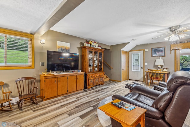 living room featuring light hardwood / wood-style flooring, a textured ceiling, ceiling fan, and plenty of natural light