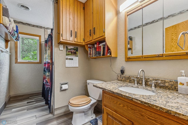 bathroom with vanity, a textured ceiling, wood-type flooring, and toilet