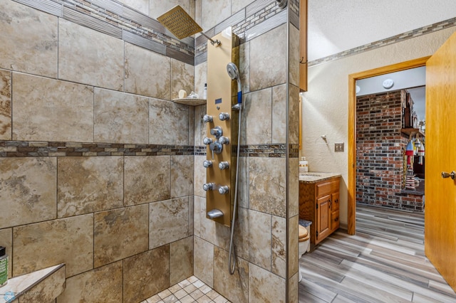 bathroom featuring vanity, crown molding, a tile shower, and hardwood / wood-style floors