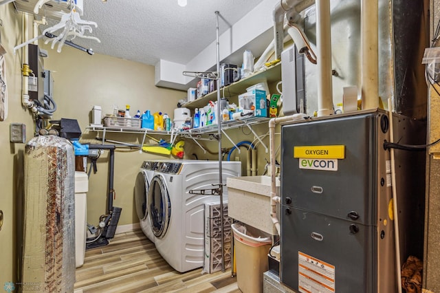 washroom with separate washer and dryer, light wood-type flooring, and a textured ceiling