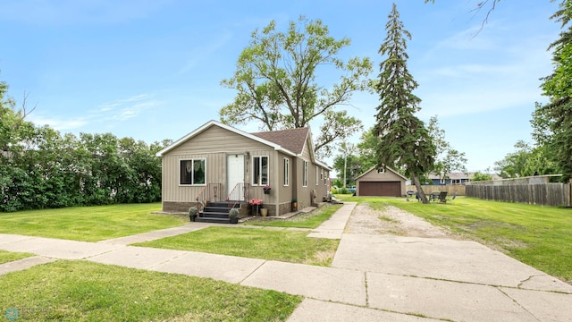 view of front of home featuring a garage, an outbuilding, and a front lawn