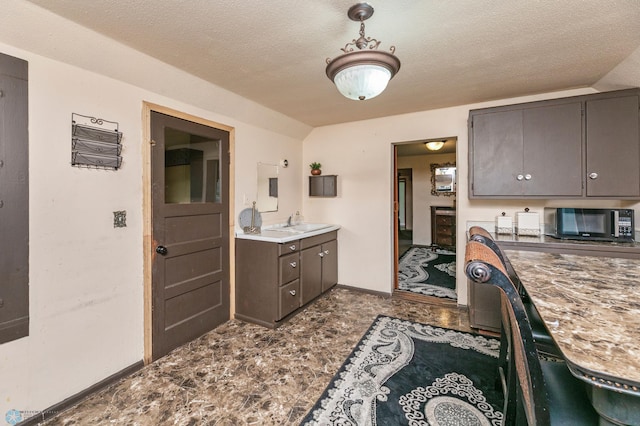 kitchen with tile patterned floors, dark brown cabinetry, and a textured ceiling