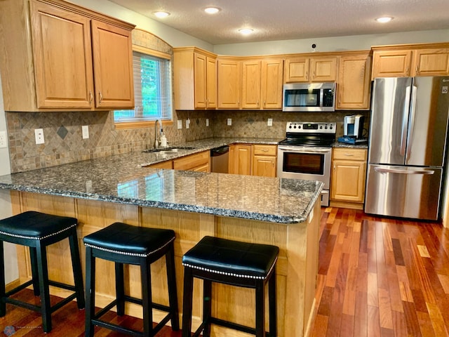 kitchen with dark hardwood / wood-style floors, stainless steel appliances, tasteful backsplash, and sink