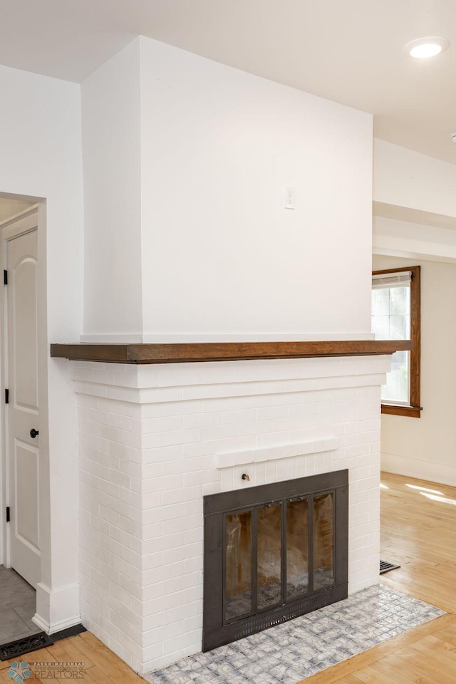 interior details featuring a brick fireplace and hardwood / wood-style floors