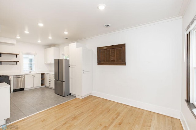 kitchen with crown molding, white cabinets, light wood-type flooring, and stainless steel appliances