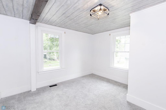 carpeted spare room with wood ceiling and plenty of natural light