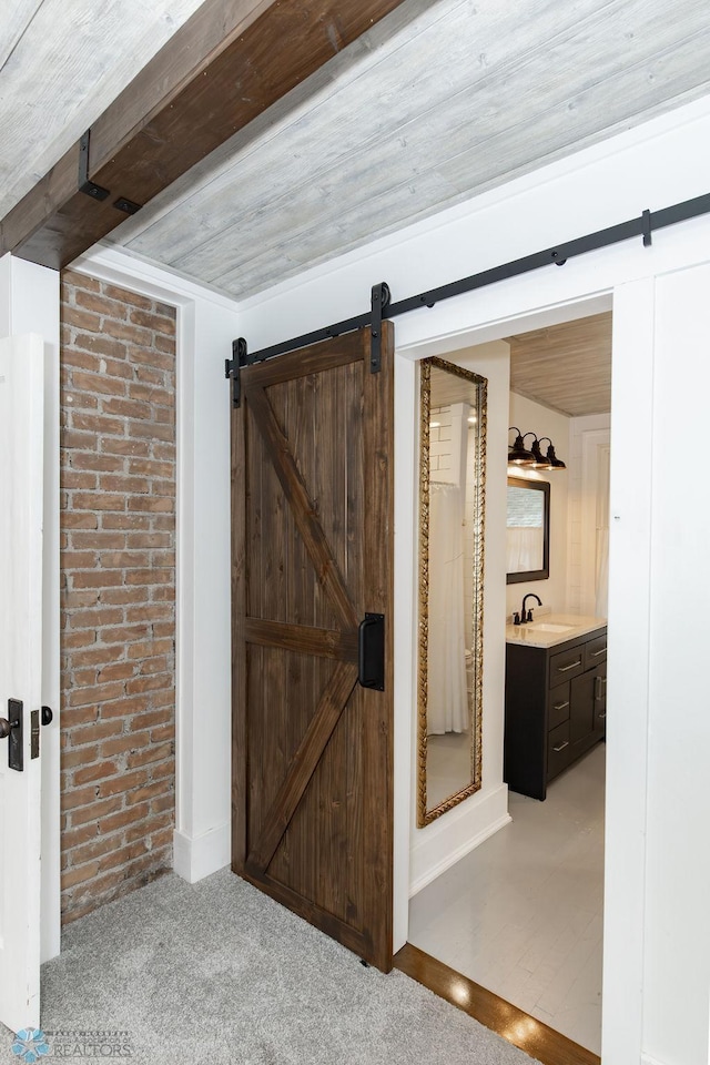 corridor featuring sink, a barn door, wooden ceiling, and carpet floors