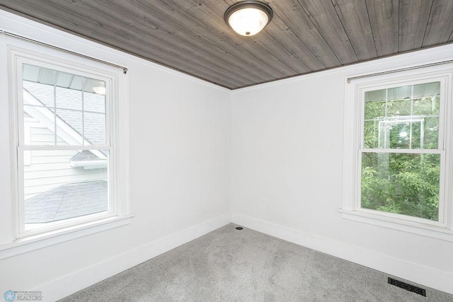 carpeted empty room featuring wood ceiling