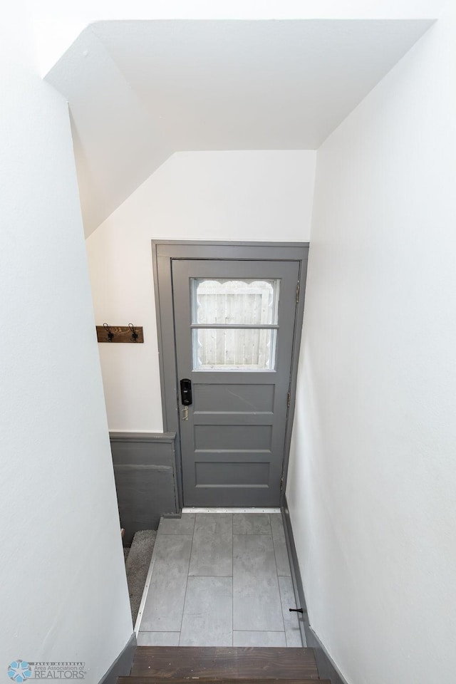 doorway to outside featuring lofted ceiling and light tile patterned floors