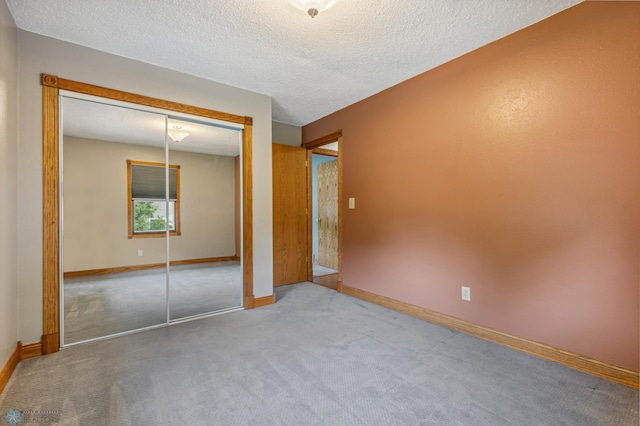 unfurnished bedroom with carpet, a textured ceiling, and a closet