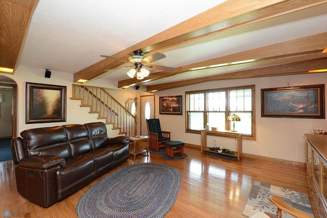 living room featuring beamed ceiling, a textured ceiling, hardwood / wood-style floors, and ceiling fan