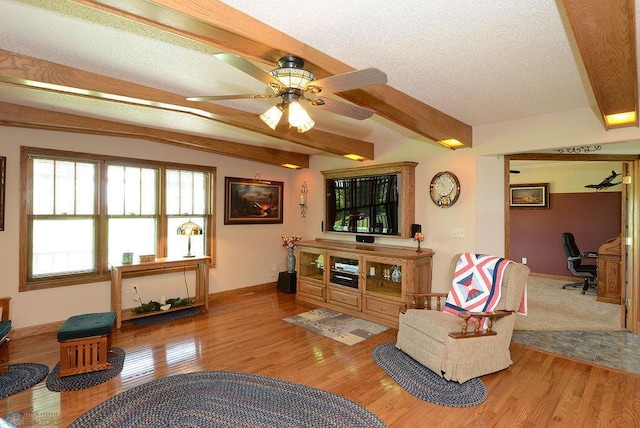 living room with beamed ceiling, a textured ceiling, ceiling fan, and hardwood / wood-style floors