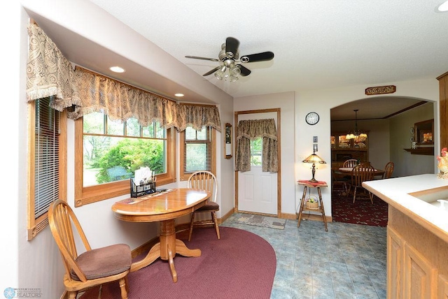 dining room with ceiling fan with notable chandelier and tile patterned flooring