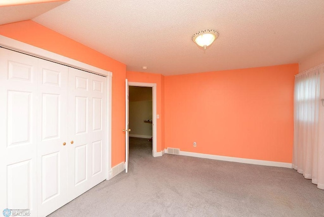 unfurnished bedroom featuring carpet flooring, a closet, and a textured ceiling