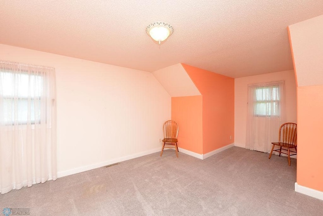 bonus room with a textured ceiling, carpet, and lofted ceiling