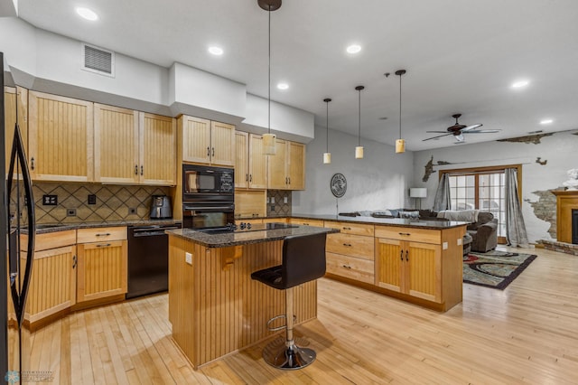 kitchen with light hardwood / wood-style flooring, black appliances, decorative light fixtures, a kitchen breakfast bar, and ceiling fan