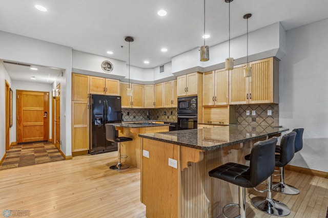 kitchen with backsplash, light hardwood / wood-style floors, black appliances, and hanging light fixtures