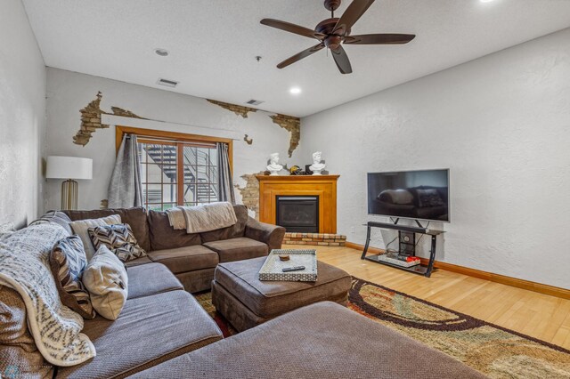 living room featuring hardwood / wood-style flooring, a brick fireplace, and ceiling fan