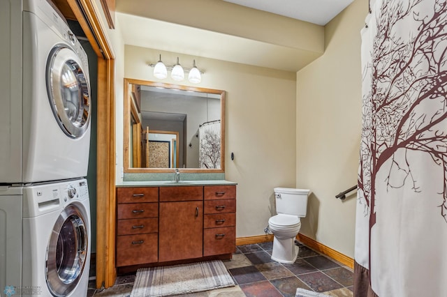 bathroom with vanity, toilet, stacked washer / drying machine, and tile patterned flooring