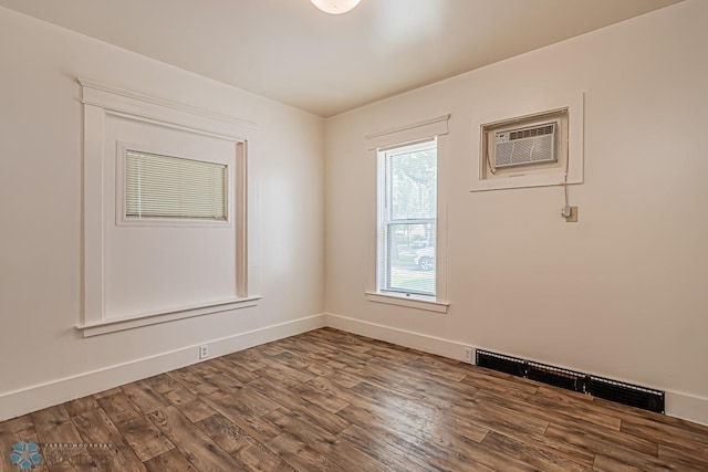 spare room featuring hardwood / wood-style flooring and an AC wall unit