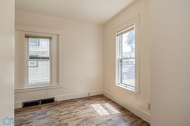 unfurnished room featuring a healthy amount of sunlight and hardwood / wood-style floors