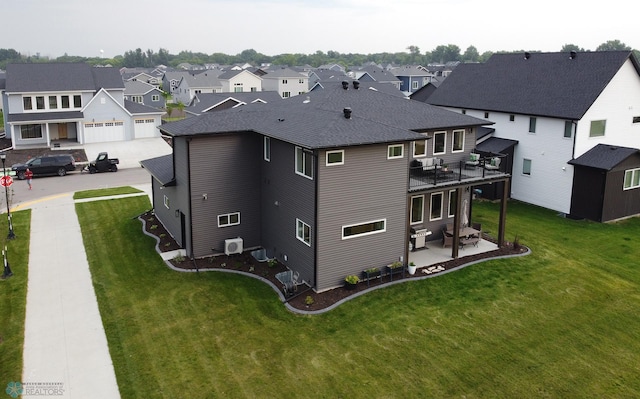 rear view of house with a balcony, a garage, a lawn, central AC unit, and a patio area