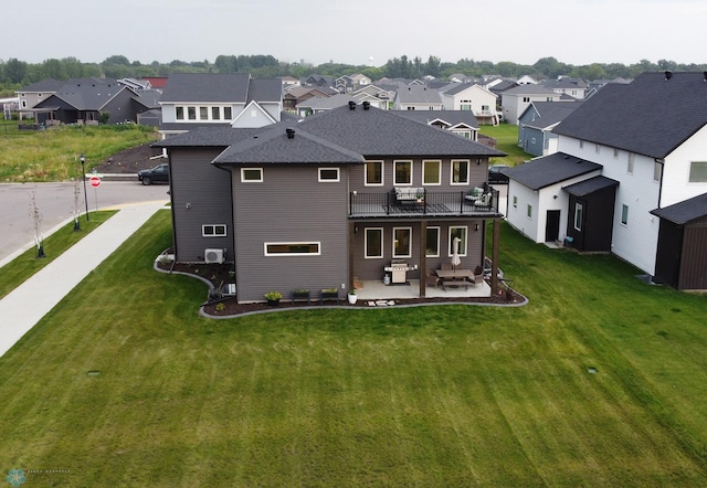 back of property featuring a balcony, a patio area, central AC, and a yard