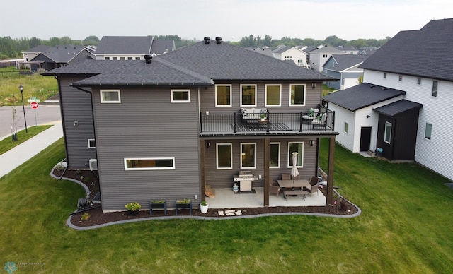 rear view of property featuring a balcony, a patio area, and a lawn