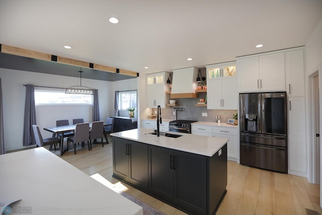 kitchen with white cabinets, backsplash, stainless steel range with gas cooktop, and fridge with ice dispenser