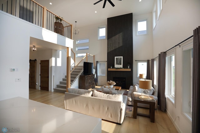 living room featuring a high ceiling, light wood-type flooring, and a large fireplace