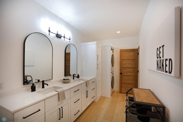 bathroom with hardwood / wood-style floors, stacked washing maching and dryer, and double sink vanity