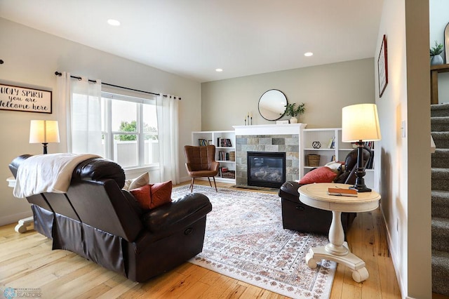 living room with a tile fireplace and light hardwood / wood-style floors