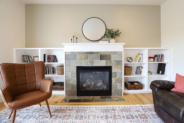 living area featuring wood-type flooring and a tiled fireplace