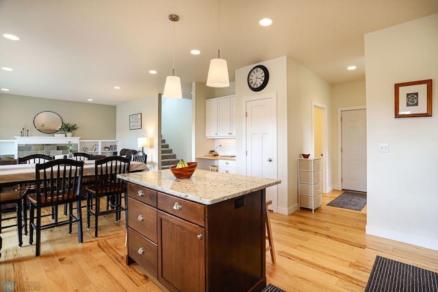 kitchen with a fireplace, light hardwood / wood-style flooring, hanging light fixtures, and a kitchen island