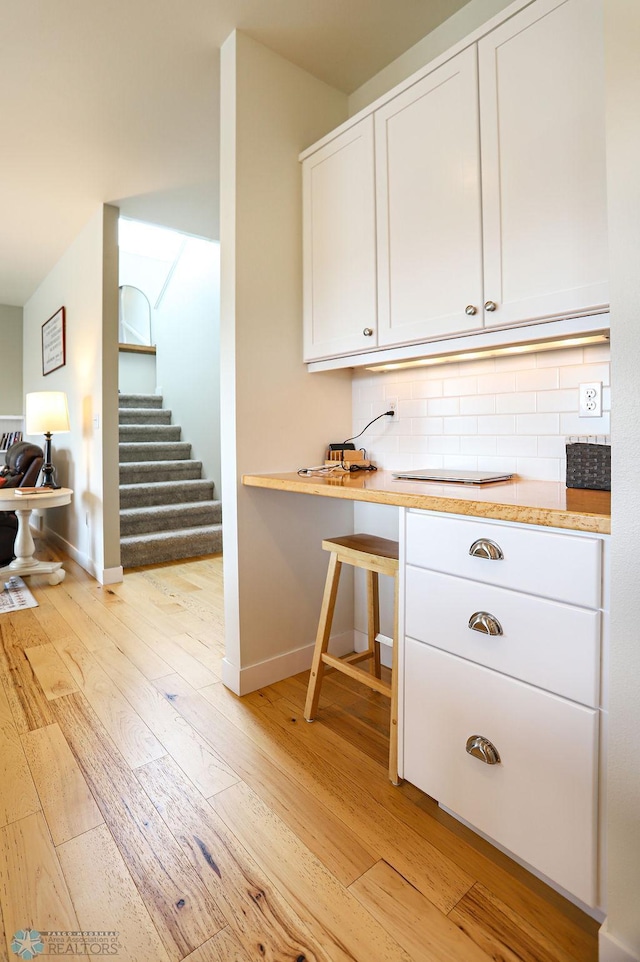 kitchen with light hardwood / wood-style flooring, white cabinets, and tasteful backsplash