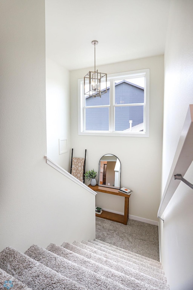 stairway with carpet floors and a chandelier