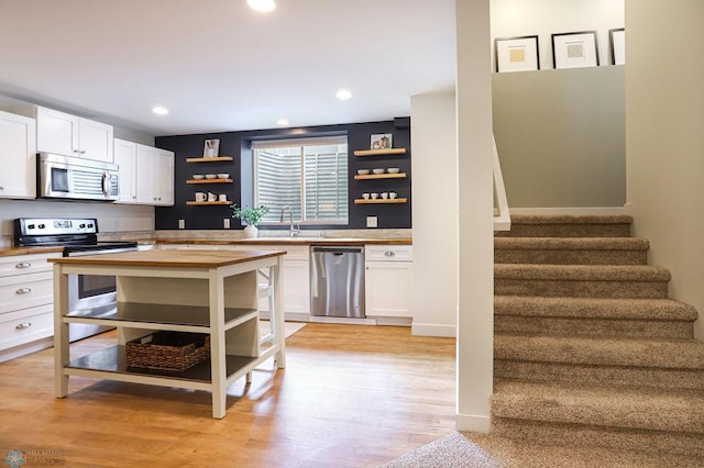 kitchen featuring appliances with stainless steel finishes, light wood-type flooring, white cabinets, and wooden counters