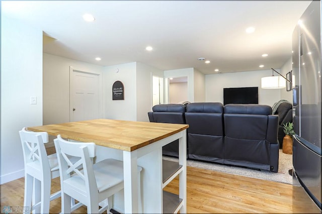 kitchen featuring light hardwood / wood-style floors, wood counters, a kitchen breakfast bar, and a kitchen island