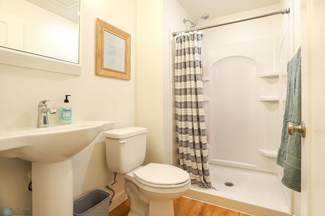 bathroom with hardwood / wood-style flooring, a shower with curtain, and toilet