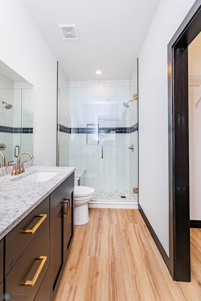 bathroom featuring vanity, toilet, an enclosed shower, and hardwood / wood-style flooring